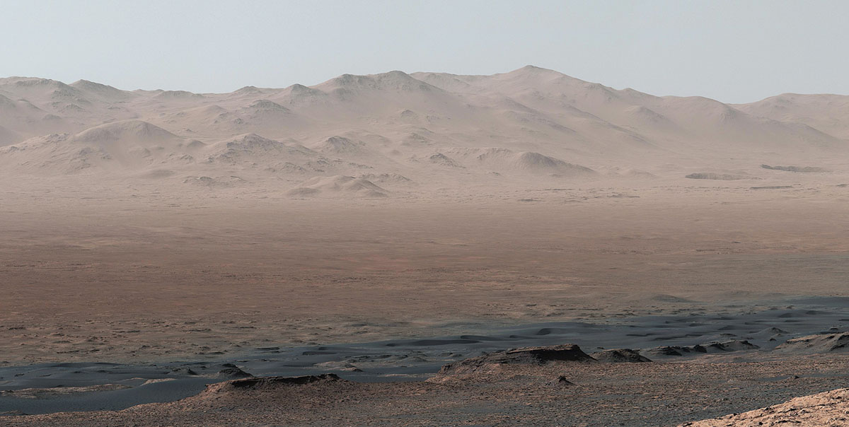 A vantage point on "Vera Rubin Ridge" provided NASA's Curiosity Mars rover this detailed look back over the area where it began its mission inside Gale Crater, plus more-distant features of the crater.This view toward the north-northeast combines eight images taken by the right-eye, telephoto-lens camera of Curiosity's Mast Camera (Mastcam). It shows more detail of a fraction of the area pictured in a more sweeping panorama (PIA22210) acquired from the same rover location using Mastcam's left-eye, wider-angle-lens camera. The scene has been white-balanced so the colors of the rock materials resemble how they would appear under daytime lighting conditions on Earth.The component images were taken on Oct. 25, 2017, during the 1,856th Martian day, or sol, of the rover's work on Mars. At that point, Curiosity had gained 1,073 feet (327 meters) in elevation and driven 10.95 miles (17.63 kilometers) from its landing site.Mount Sharp stands about 3 miles (5 kilometers) high in the middle of Gale Crater, which spans 96 miles (154 kilometers) in diameter. Vera Rubin Ridge is on the northwestern flank of lower Mount Sharp. The right foreground of this panorama shows a portion of Vera Rubin Ridge. In the distance is the northern wall of Gale Crater, with the rim crest forming the horizon roughly 25 miles (40 kilometers) from the rover's location. (NASA/JPL-Caltech/MSSS)