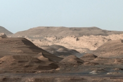 This composite image looking toward the higher regions of Mount Sharp was taken on September 9, 2015, by NASA's Curiosity rover. In the foreground -- about 2 miles (3 kilometers) from the rover -- is a long ridge teeming with hematite, an iron oxide. Just beyond is an undulating plain rich in clay minerals. And just beyond that are a multitude of rounded buttes, all high in sulfate minerals. The changing mineralogy in these layers of Mount Sharp suggests a changing environment in early Mars, though all involve exposure to water billions of years ago. The Curiosity team hopes to be able to explore these diverse areas in the months and years ahead. Further back in the image are striking, light-toned cliffs in rock that may have formed in drier times and now is heavily eroded by winds.The colors are adjusted so that rocks look approximately as they would if they were on Earth, to help geologists interpret the rocks. This "white balancing" to adjust for the lighting on Mars overly compensates for the absence of blue on Mars, making the sky appear light blue and sometimes giving dark, black rocks a blue cast. (NASA/JPL-Caltech/MSSS)